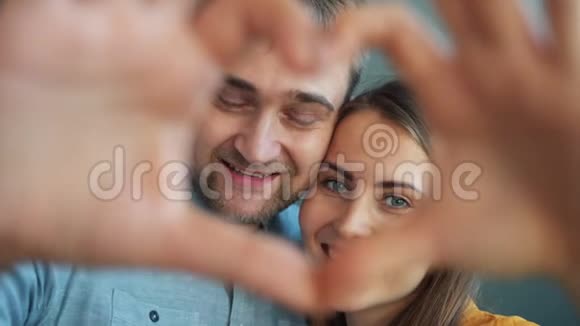 一对幸福夫妇的肖像用双手微笑着看着镜头呈现出心形视频的预览图