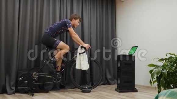 有动力的人骑着固定的自行车教练看着绿色的屏幕室内自行车概念做有氧运动的年轻人视频的预览图