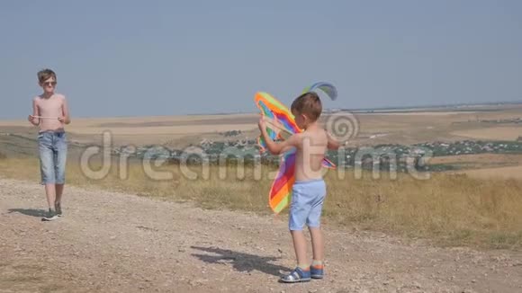 一个男孩带着风筝沿着路跑梦想飞翔孩子们游戏蓝天背景下的男孩视频的预览图