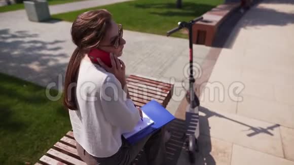 时尚时髦的女人用手机进行对话电子滑板车生态技术户外小工具视频的预览图