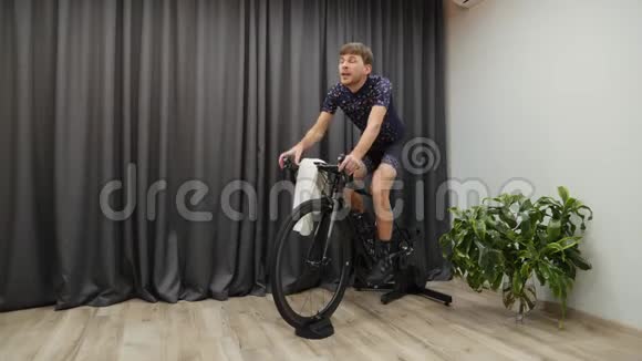 室内自行车的概念年轻骑自行车的人在家骑自行车刻苦训练骑自行车运动时男性出汗视频的预览图