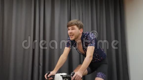 室内自行车概念骑自行车的人智能教练在家骑自行车准备比赛的专业自行车运动员男性艰苦训练视频的预览图