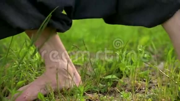在户外草地上特写练习者的腿在气功练习中赤脚穿越a的概念视频的预览图