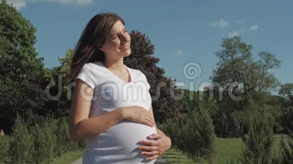 在阳光明媚的夏日外面的孕妇享受温暖和阳光视频的预览图