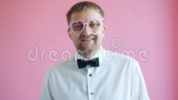 心形眼镜中的帅哥在粉色背景上对着镜头微笑的画像视频的预览图