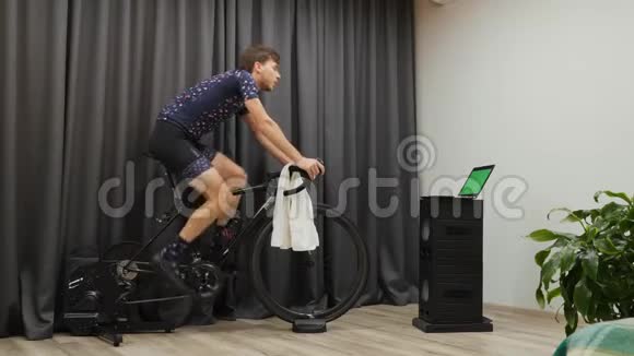 在家骑自行车的时候男人出汗男性在室内循环锻炼时用毛巾擦拭年轻的自行车手视频的预览图