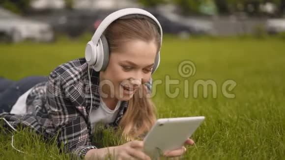 那个女孩正在公园里休息女孩用大耳机听大自然的音乐并在视频的预览图