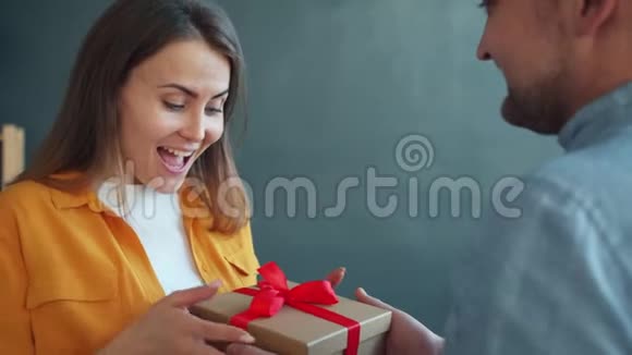 令人兴奋的年轻女子从男朋友那里得到礼物感到在公寓里很快乐视频的预览图