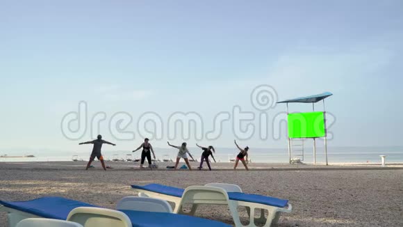 早上在卵石滩练习瑜伽的运动员小组视频的预览图