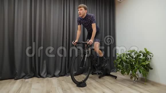 室内自行车概念年轻的男性骑自行车在智能教练男人在室内骑自行车视频的预览图