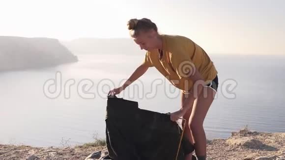 那个女孩露营后拆开了一个帐篷旅游女孩穿着黄色T恤摘下帐篷野外露营女性视频的预览图