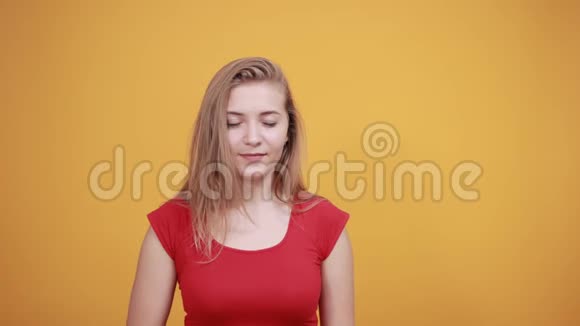 年轻的金发女孩穿着红色t恤在橙色的背景下表现出情绪视频的预览图