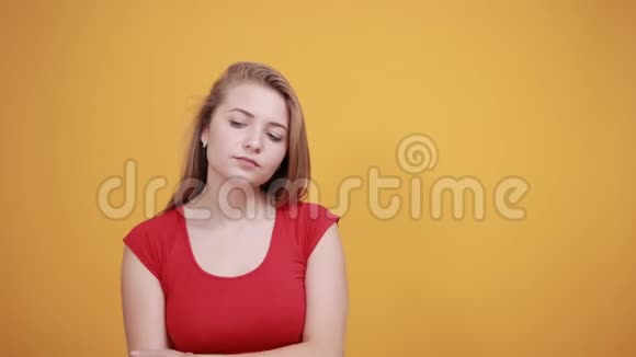 年轻的金发女孩穿着红色t恤在橙色的背景下表现出情绪视频的预览图