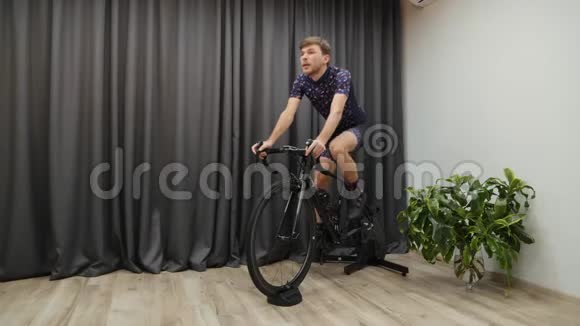 男性在室内骑自行车时饮用水或等渗饮料室内自行车概念人体训练视频的预览图