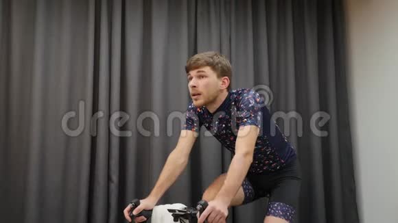 手动硬踏板在循环智能教练室内特写年轻健康的男性骑自行车和解开运动衫专业人员视频的预览图