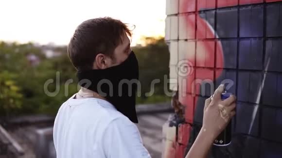 一个穿着白色T恤和黑色围巾的年轻人站在墙旁边的一张脸上涂鸦和涂鸦视频的预览图
