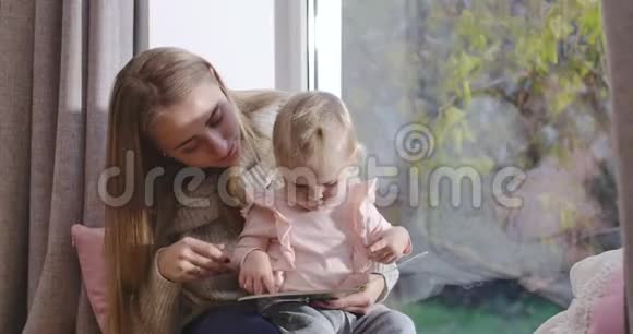 高加索母婴坐在窗台看书特写年轻漂亮的女子教育视频的预览图