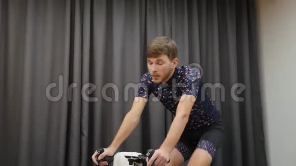 在室内骑自行车训练时为运动型男性提供饮用水等张手拿酒瓶骑自行车视频的预览图