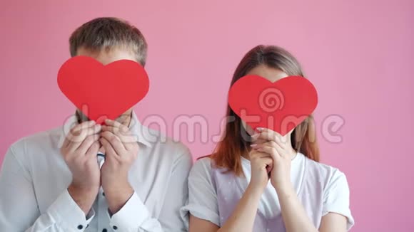 快乐的情侣在情人节卡片后面慢慢地隐藏着笑脸视频的预览图