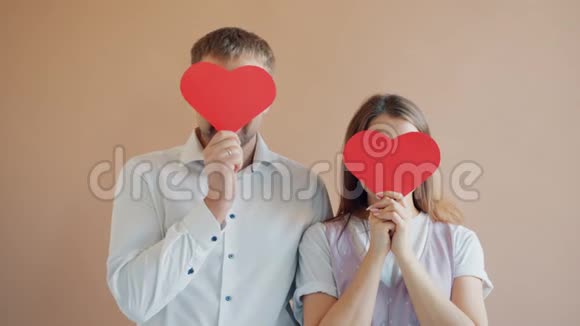 两个女孩和男人用心形情人节卡片遮住脸的肖像视频的预览图
