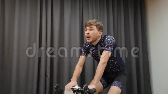 将骑自行车的人踩起来智能训练器和擦拭毛巾的脸适合男性运动员在室内骑自行车视频的预览图