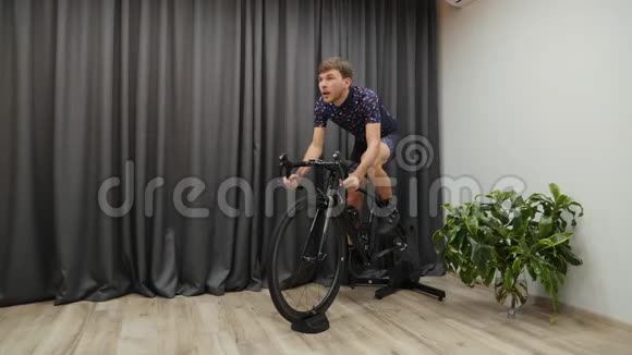 男子密集蹬自行车教练男子在室内骑自行车室内虚拟自行车男子骑自行车冲刺视频的预览图