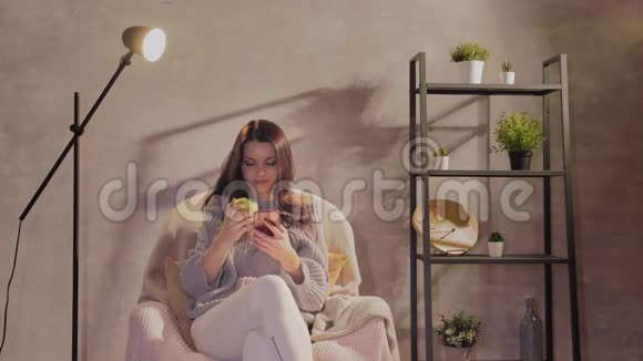 一个年轻漂亮的女人坐在椅子上在手机上留言视频的预览图