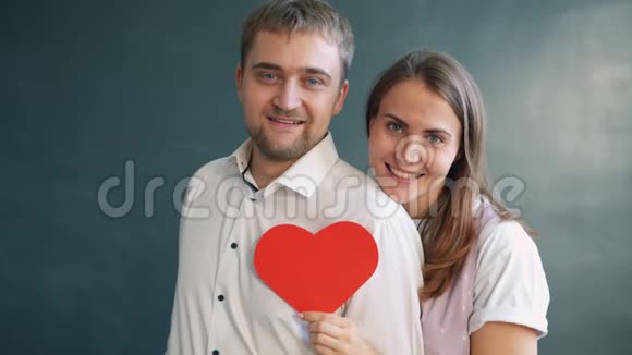快乐的异性情侣一起捧着心形情人节卡片微笑视频的预览图