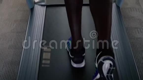 穿着蓝色运动鞋的非裔美国运动员在健身俱乐部的电动跑步机上锻炼不要脸的男跑步者视频的预览图