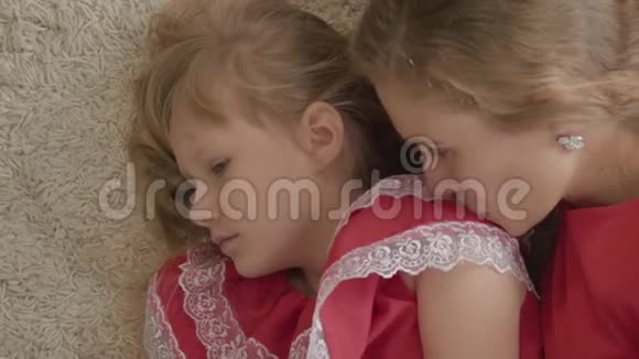 俯视图年轻女子亲吻小女孩肩膀的特写镜头母亲和女儿穿着红色的衣服躺在柔软的视频的预览图