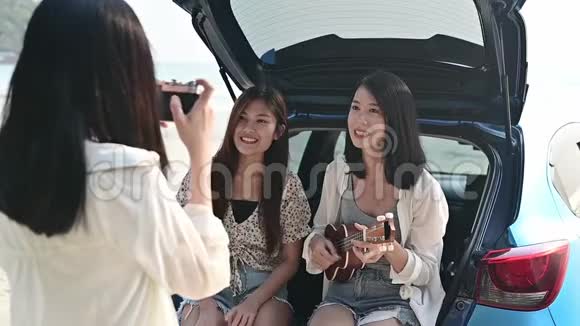 亚洲妇女在海滩上演奏音乐和唱歌暑假旅游泰国放松和娱乐视频的预览图