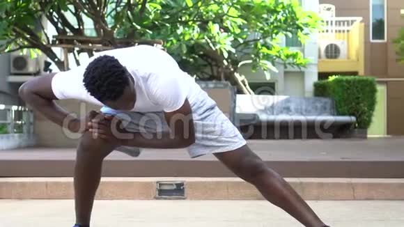 美国黑人运动员在晴天在公园训练时做伸展运动视频的预览图