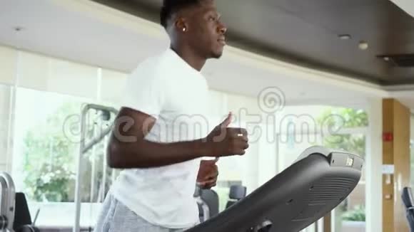 下面是一位白天在健身房里用电动跑步机跑步的非洲裔美国人正在训练的运动员视频的预览图