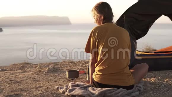 后视画面中一个孤独的金发女孩穿着黄色T恤坐在地上望着地平线露营车燃烧器视频的预览图