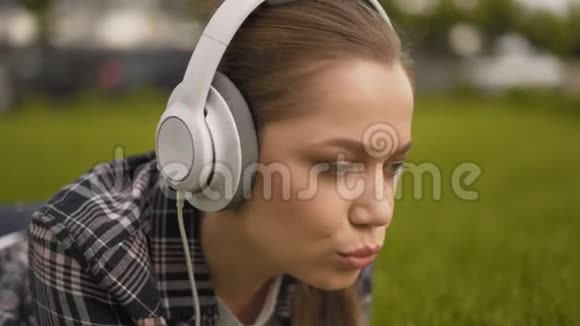特写镜头学生女孩脸戴耳机的女孩听音乐唱歌视频的预览图