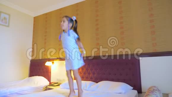 一个小女孩跳在酒店房间的床上玩得很开心享受生活视频的预览图