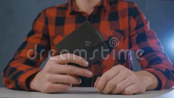 男人坐在家里的桌子上时双手合拢手里拿着一个没有钱的皮夹金融业务视频的预览图