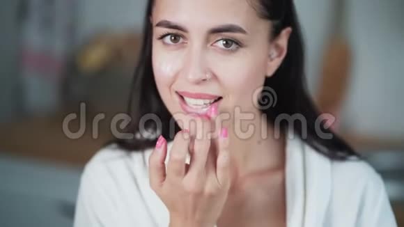 女人在嘴唇上涂润唇膏脸上涂霜视频的预览图