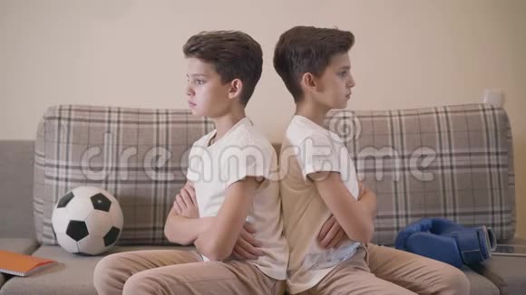两对白种人黑发双胞胎背靠背坐着的肖像两兄弟转身看着他们视频的预览图