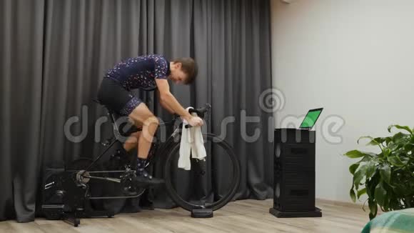 人硬蹬出马鞍和密集自行车的家庭智能教练室内有动力的男性短跑和做间隔视频的预览图