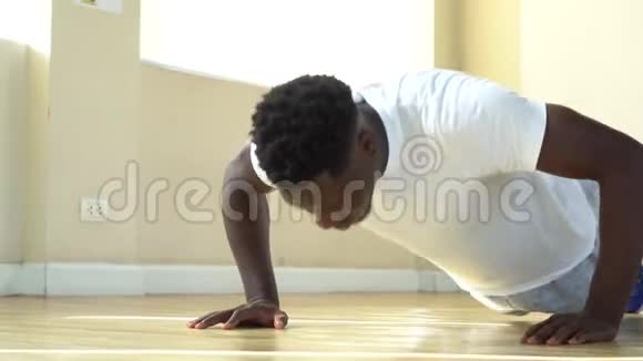 年轻的非裔美国人在地板上做俯卧撑锻炼期间锻炼的有决心的男运动员视频的预览图