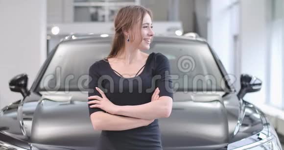 年轻白种人女孩的肖像看着远离和微笑的站在汽车经销商美丽的女人视频的预览图