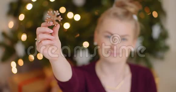 女人拿着雪花状的饼干在圣诞树上视频的预览图