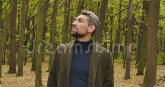 一个英俊的白发白种人的特写棕色的眼睛站在森林里环顾四周他就是视频的预览图