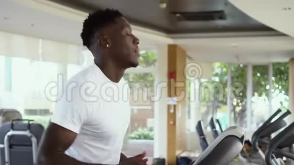 下面是一位白天在健身房里用电动跑步机跑步的非洲裔美国人正在训练的运动员视频的预览图