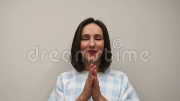 女人在白色背景下祈祷交易成功年轻微笑的女性在摄影棚里祈祷视频的预览图