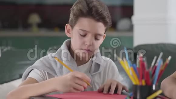 黑种人白人小学生坐在桌子旁学习的特写照片可爱的男孩在运动中写下视频的预览图
