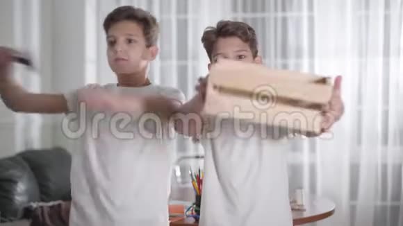 开朗的白种人双胞胎兄弟在镜头前吹嘘他们的木制品一个男孩高兴地跳舞他的兄弟姐妹表现得很酷视频的预览图