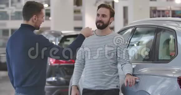 两个白人男子站在汽车经销商的肖像从新汽车上掏出钥匙握手商人和视频的预览图