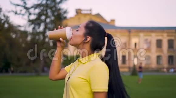 一个外表东方的年轻女孩在校园里喝咖啡4K视频的预览图